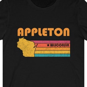 Może przedstawiać: Czarny T-shirt z grafiką w stylu vintage przedstawiającą stan Wisconsin z napisem "APPLETON" i "WISCONSIN" w kolorze pomarańczowym.