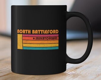 May include: Black coffee mug with a retro-style design featuring the text "NORTH BATTLEFORD *SASKATCHEWAN" in white and orange.