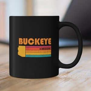May include: Black ceramic coffee mug with a retro-style graphic of the state of Arizona with the text "Buckeye * Arizona" printed on it.