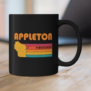 May include: Black coffee mug with a retro design featuring the word "APPLETON" in orange and yellow letters. The design also includes a silhouette of the state of Wisconsin with a star and the word "WISCONSIN" in white letters.