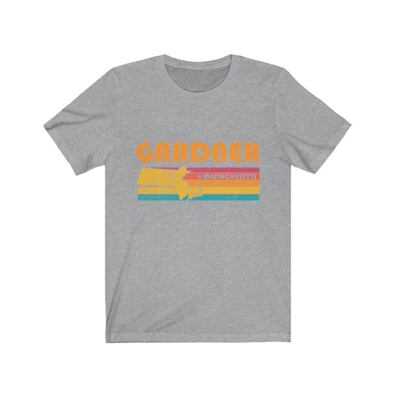 May include: A heather grey t-shirt with a retro-style graphic of the state of Massachusetts with the word "GARDNER" and "MASSACHUSETTS" printed in orange.