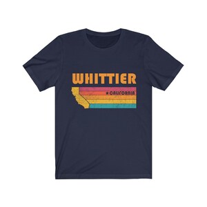 May include: Navy blue t-shirt with a vintage-style graphic of the state of California with the text "WHITTIER" and "*CALIFORNIA" in orange.