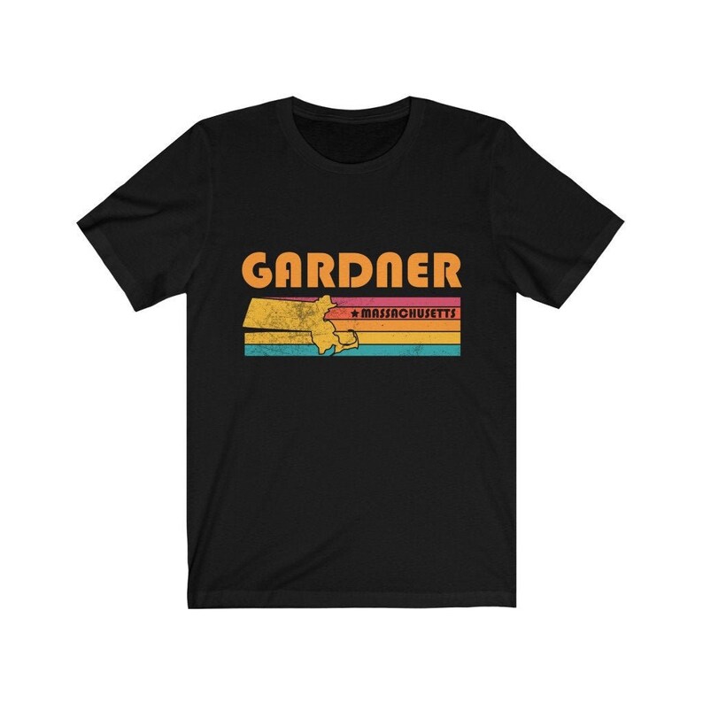 May include: Black t-shirt with a vintage-style graphic of the state of Massachusetts with the word "GARDNER" and "MASSACHUSETTS" in orange text.