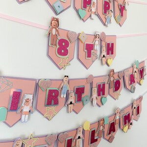 Puede incluir: Bandera de cumplea&ntilde;os rosa y morada con las palabras "Happy 8th Birthday Llama" en letras rosas brillantes. La bandera est&aacute; decorada con corazones, estrellas y peque&ntilde;as figuras de personas con diferentes atuendos.
