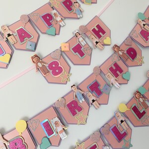 Puede incluir: Bandera rosa y morada con las palabras "Happy 8th Birthday" en letras de purpurina rosa. La bandera est&aacute; decorada con estrellas, corazones, diamantes y peque&ntilde;as figuras de personas.