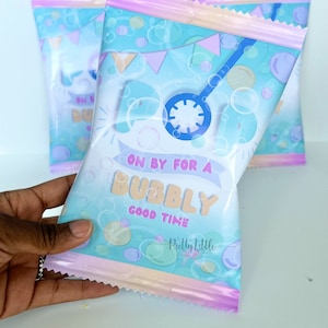 May include: A pink and blue party favor bag with a bubble design. The bag has the text "On by for a Bubbly Good Time" and a logo that says "Pretty Little".