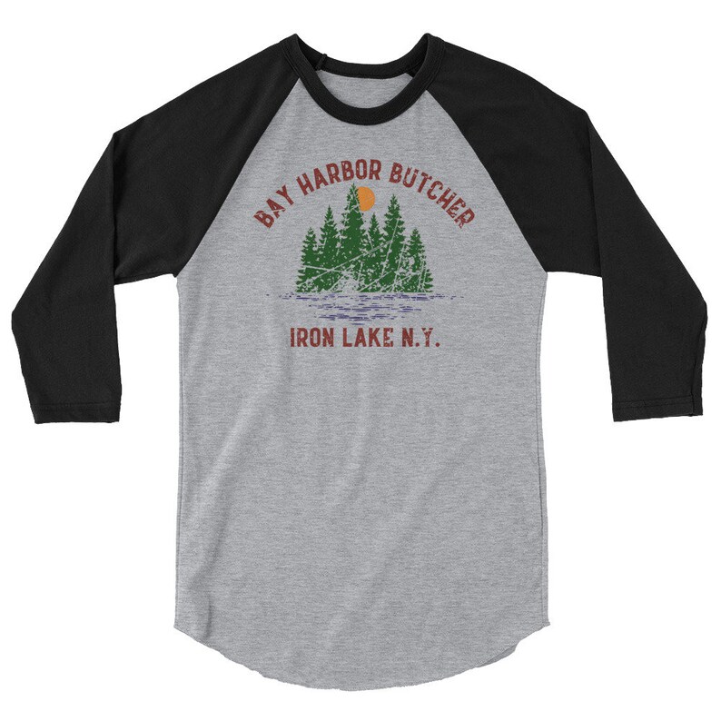 May include: A black and grey baseball tee shirt with a vintage design. The text on the shirt reads "Bay Harbor Butcher Iron Lake N.Y.".