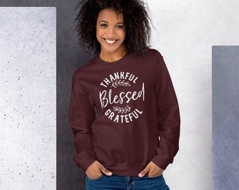 May include: A maroon sweatshirt with a white graphic print that says "Thankful Blessed Grateful" with a leaf design.
