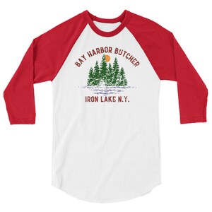 May include: A white and red baseball tee shirt with a green and brown graphic of a forest scene with the text "Bay Harbor Butcher Iron Lake N.Y."