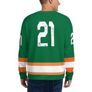 May include: Green and white long-sleeved sweatshirt with orange stripes and the number "21" on the back.