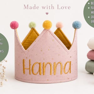 Pode incluir: Uma coroa de tecido rosa com pintas douradas e o nome Hanna bordado em fio dourado. A coroa é rematada com cinco pequenos pompons nas cores rosa, verde-claro, amarelo, pêssego e azul. O forro interior é de tecido amarelo mostarda.
