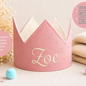 Könnte beinhalten: Eine Krone aus altrosa Stoff mit dem in cremefarbener Schreibschrift gestickten Namen Zoe. Die Krone ist mit kleinen goldenen Punkten verziert und hat ein cremefarbenes Innenfutter. Der Text 032 rosewood / 038 creme Zoe - Schrift / font #13 in creme ist sichtbar.