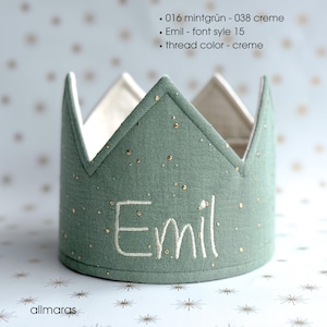 Könnte beinhalten: Ein mintgrünes Stoffkrone mit goldenen Sprenkeln und dem Namen "Emil" in Weiß gestickt. Die Krone hat eine cremefarbene Innenseite und ist mit spitzen Zacken versehen. Der Markenname "allmaras" steht unten.