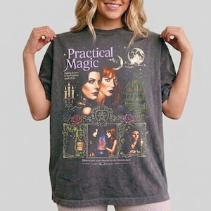 Puede incluir: Una camiseta de manga corta gris carbón con un estampado gráfico con el texto Practical Magic. El diseño incluye ilustraciones de dos mujeres, una casa, un gato negro, velas y un pentagrama, con el texto is the trickiest spell of all.