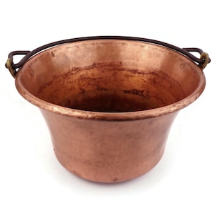 Puede incluir: Una olla de cobre con un asa de metal negro. La olla está vacía y tiene una superficie brillante ligeramente deslustrada.