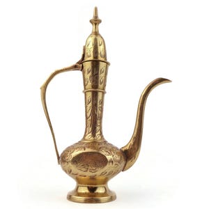Peut inclure: Une théière en métal de couleur dorée avec des motifs floraux complexes. La théière a un corps rond et un bec long et incurvé.
