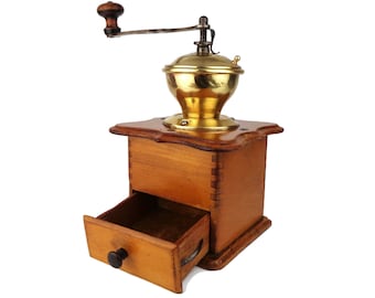 May include: A vintage wooden coffee grinder with a brass top and a drawer for storing coffee beans. The grinder has a crank handle and is in good condition.