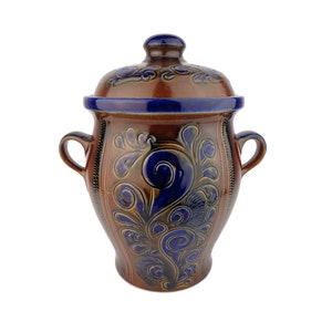 May include: A brown ceramic jar with a lid, decorated with blue floral patterns. The jar has two handles on the sides.