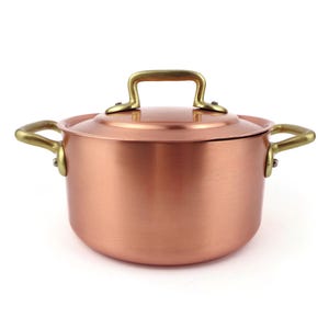 Peut inclure: Une casserole de cuisine de couleur cuivre avec un couvercle et des poignées en laiton. La casserole a un corps arrondi et un couvercle avec une poignée en laiton. Les poignées latérales sont également en laiton.