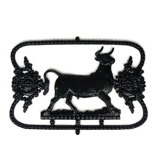Peut inclure: Silhouette noire en métal d'un taureau avec des détails floraux ornés de chaque côté. Le taureau se tient sur une petite base.