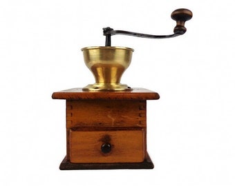 May include: A vintage wooden coffee grinder with a brass hopper and a black metal crank. The grinder has a drawer for collecting the ground coffee.