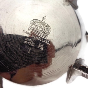 Puede incluir: Azucarero de plata con una corona y el texto "Made in Holland" y "233 1/2" en la parte inferior.