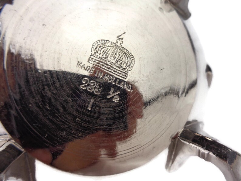 Puede incluir: Azucarero de plata con una corona y el texto "Made in Holland" y "233 1/2" en la parte inferior.