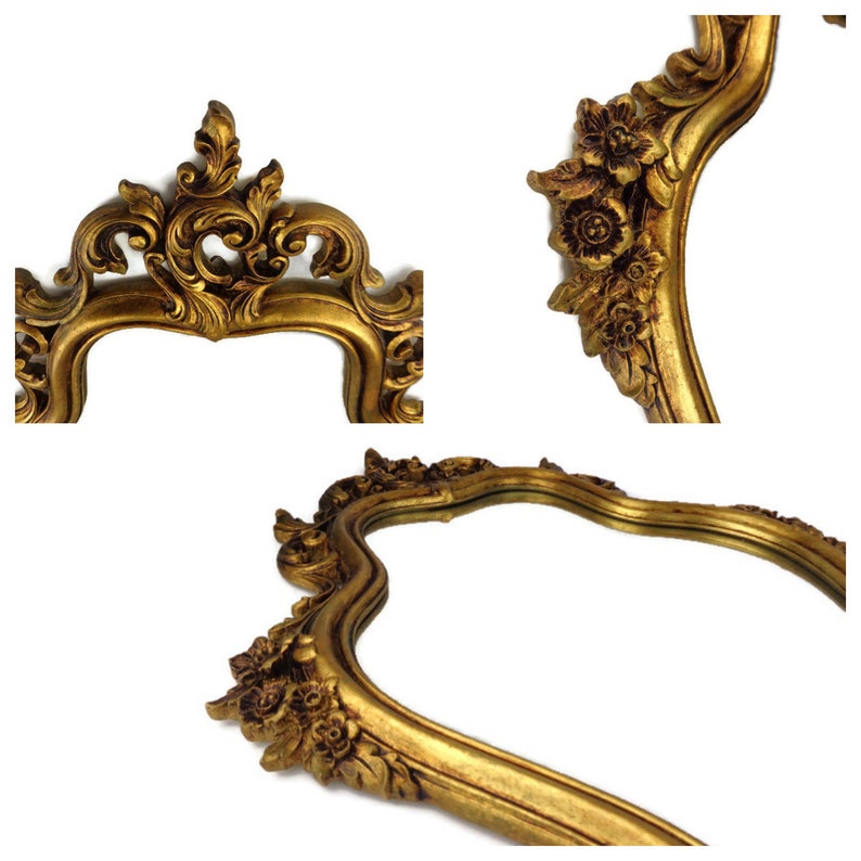 May include: A gold-toned ornate mirror with a decorative frame featuring intricate floral and scrollwork details.