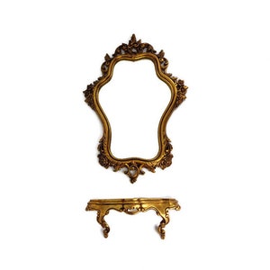 May include: A gold ornate mirror with a decorative frame and a shelf underneath. The mirror is shaped like a teardrop and has a scalloped edge.