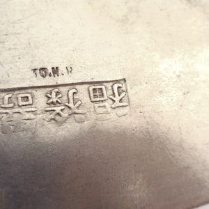 May include: Close-up of a silver metal object with the text "T.O.M.H." and a series of Japanese characters.
