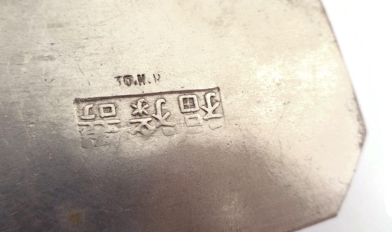 May include: Close-up of a silver metal object with the text "T.O.M.H." and a series of Japanese characters.