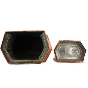May include: A copper-colored hexagonal box with a lid. The box is open and the inside is lined with a silver-colored material.