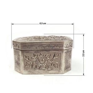 May include: A silver octagonal box with intricate floral carvings. The box measures 6.5 inches in length and 3.5 inches in height.