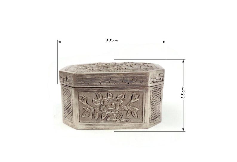 May include: A silver octagonal box with intricate floral carvings. The box measures 6.5 inches in length and 3.5 inches in height.