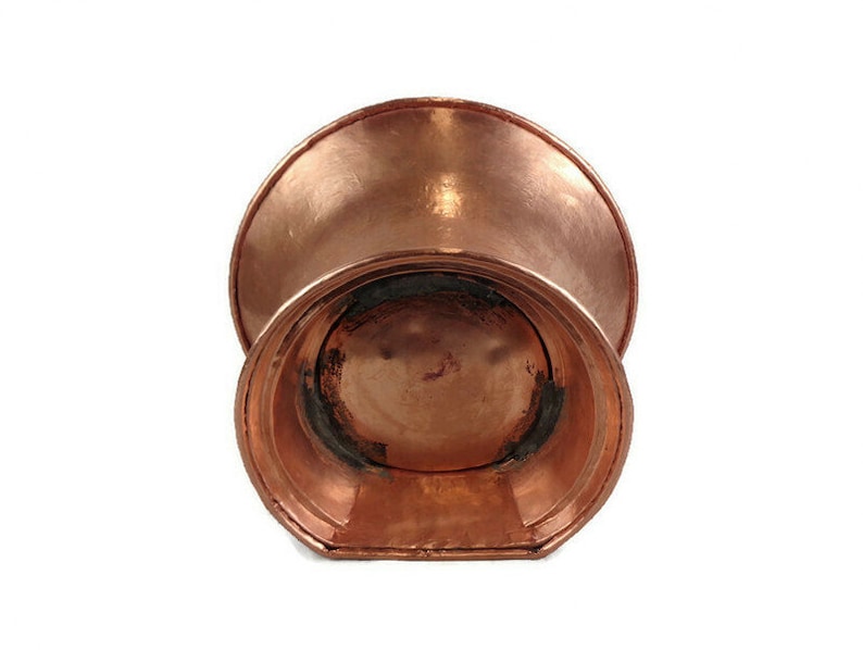 May include: A copper planter with a wide, flared top and a rounded bottom. The planter has a smooth, polished finish.