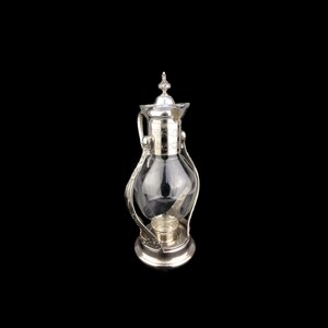 May include: Silver and glass beverage dispenser with a decorative handle and a base with a candle holder.