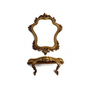 May include: A gold-colored ornate mirror with a decorative frame and a matching gold-colored vanity table with a shelf.