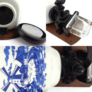 May include: A white ceramic jar with a blue and white windmill design. The jar has a black lid and is attached to a wooden base with a black metal grinder. The grinder has a glass jar for storing spices.