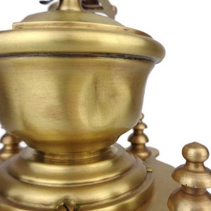 May include: A vintage brass coffee grinder with a round, ornate top and a decorative base. The grinder has a smooth, polished finish and intricate details.