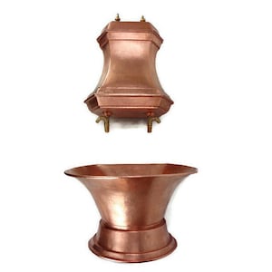 May include: A copper bathtub with a copper faucet and spout. The bathtub is freestanding and has a rounded shape. The faucet is attached to a wall-mounted copper fixture.