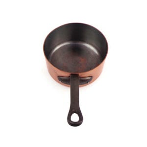 May include: A round copper saucepan with a dark metallic interior and a long, dark, heavy-duty iron handle attached with two rivets. The exterior of the pan features a polished copper finish, while the handle includes a circular hole at the end.