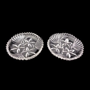 May include: Two clear glass plates with a floral design. The plates have a scalloped edge and are perfect for serving snacks or desserts.