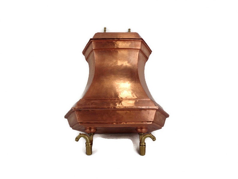 May include: A copper water dispenser with a hexagonal top and three brass spouts. The dispenser has a hammered finish and sits on three brass legs.