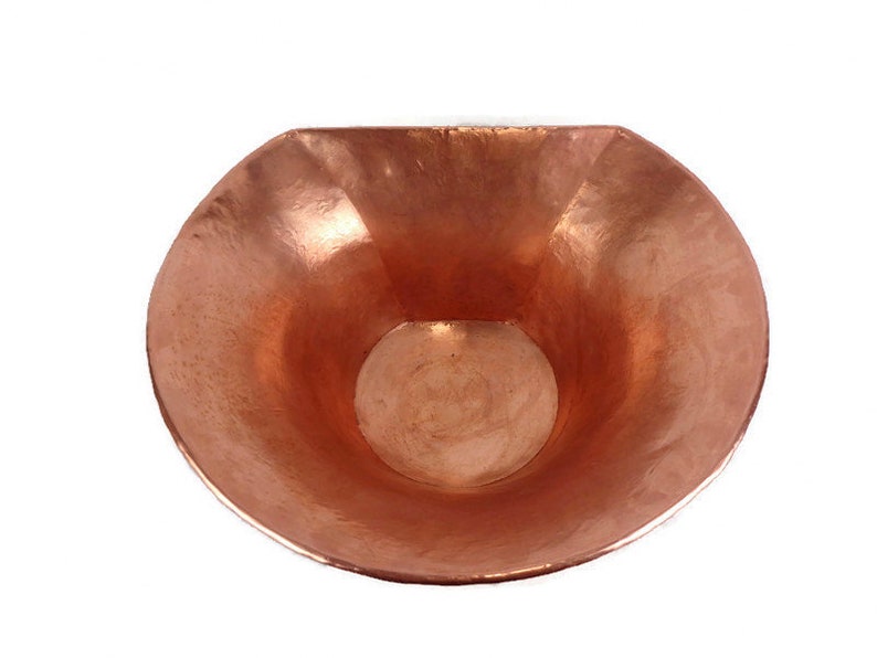May include: A copper bowl with a hammered finish. The bowl is half-round and has a wide, shallow opening.
