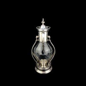 May include: A silver and glass coffee pot with a decorative design. The pot has a clear glass body and a silver lid with a finial.