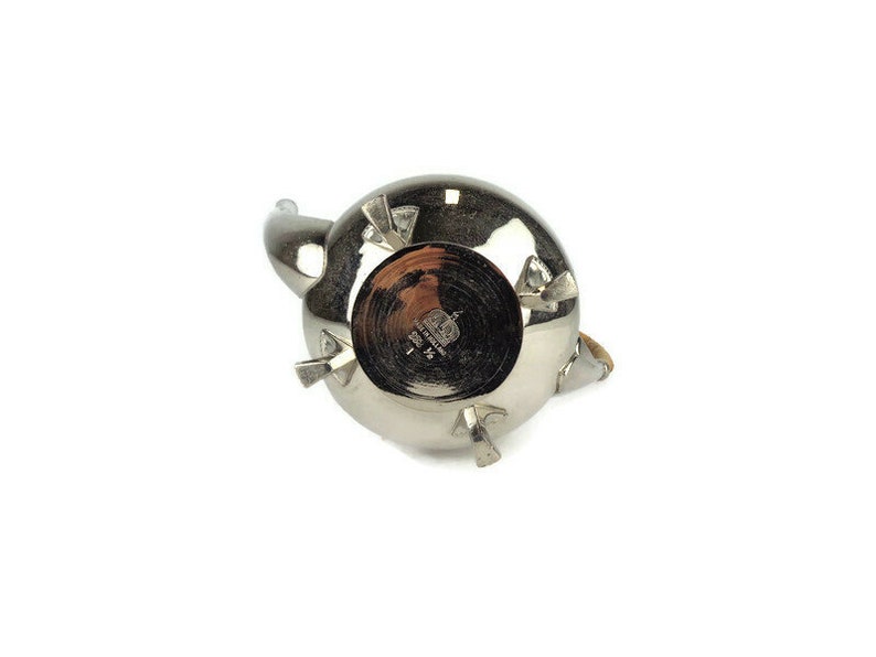 Puede incluir: Tetera de plata con asa de madera y un dise&ntilde;o en forma de estrella en la base. La tetera tiene una marca del fabricante que dice "Royal Copenhagen Denmark".