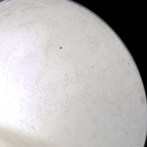 May include: Close-up of the bottom of a silver-plated pitcher with the inscription "Silver-plated England" on the bottom.