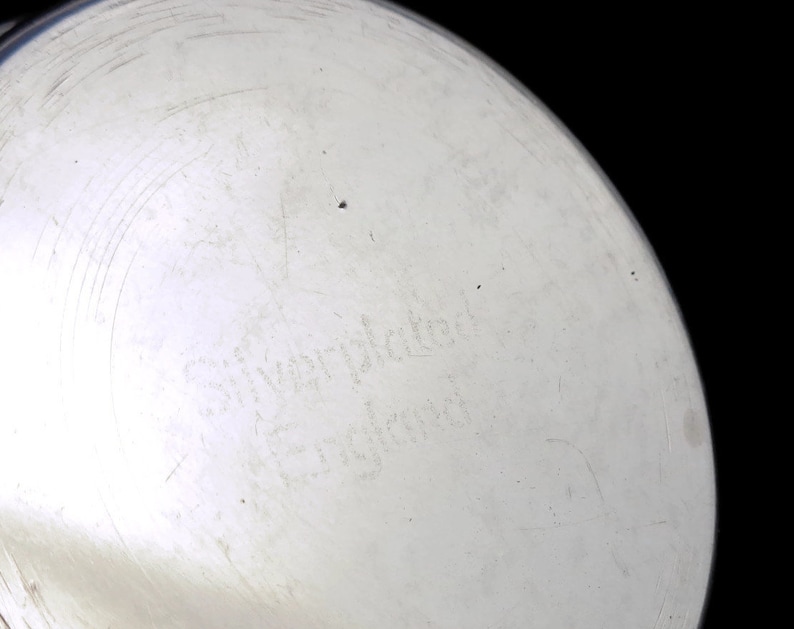 May include: Close-up of the bottom of a silver-plated pitcher with the inscription "Silver-plated England" on the bottom.
