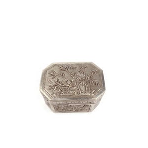May include: A silver trinket box with an intricate design of bamboo plants and birds. The box is octagonal in shape and has a hinged lid.