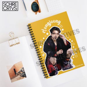 May include: A yellow spiral notebook with a black and white photo of a man with black hair and a microphone. The man is wearing a black jacket, a red and black plaid shirt, and black pants. The text "Hongjoong" is written in white on the notebook.